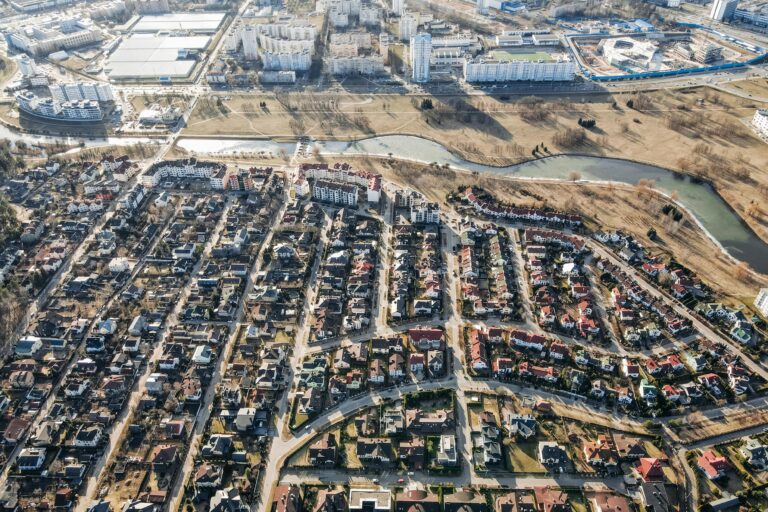 High aerial view of a suburban neighborhood alongside urban cityscape on a clear day.